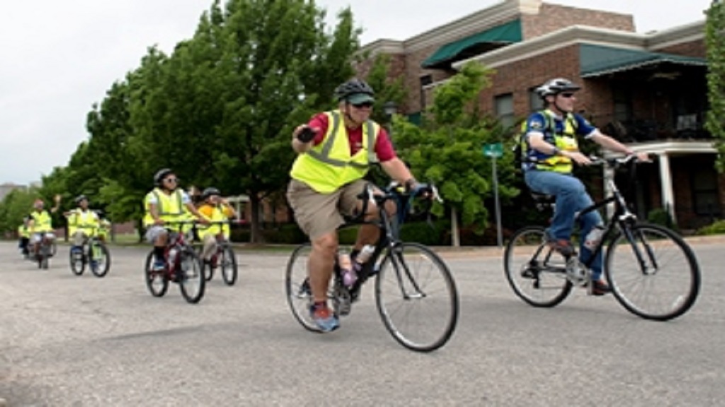 Adults and students riding their bikes in the street.