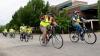 Adults and students riding their bikes in the street.