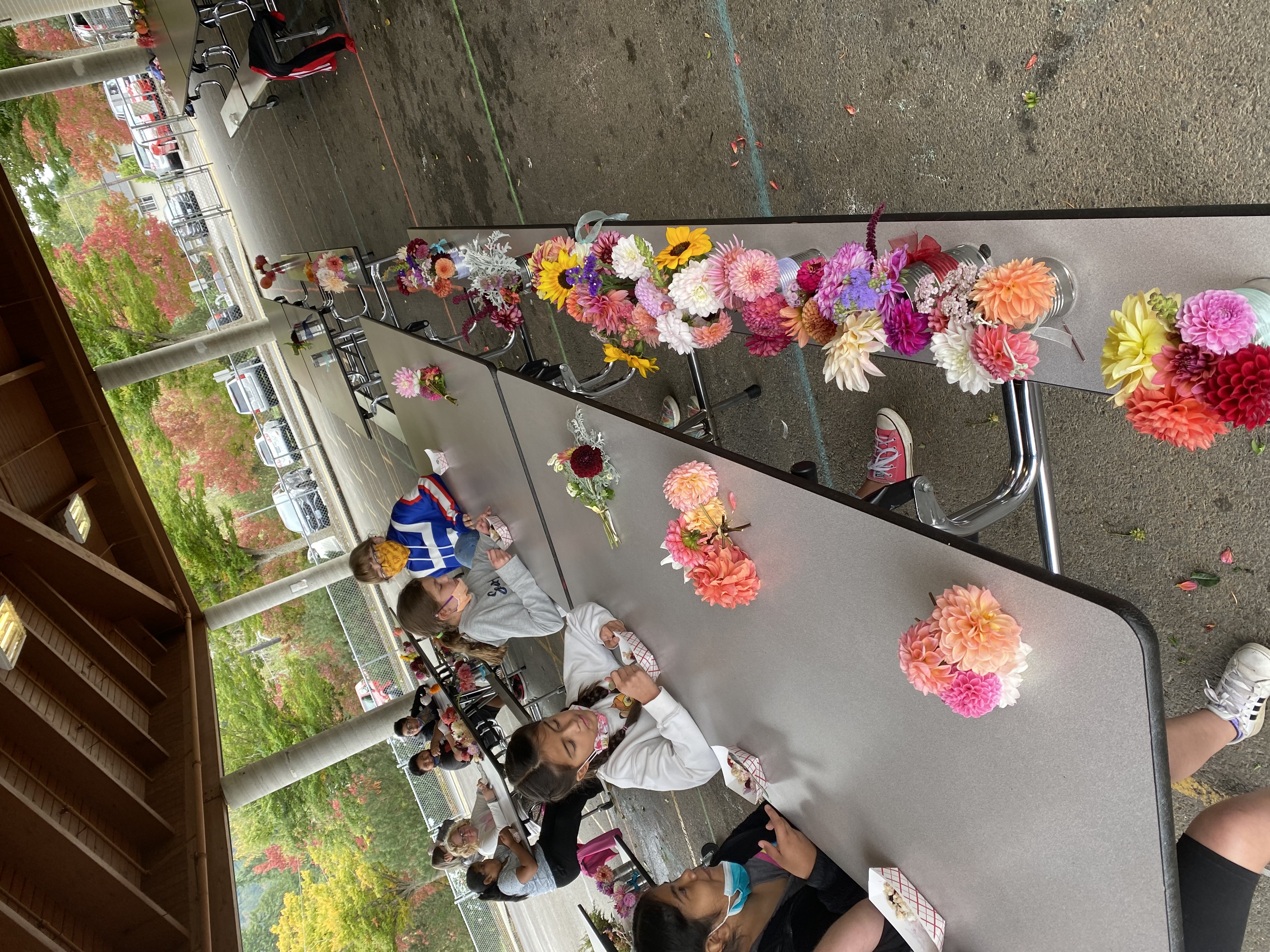 Students at table with rows of flower arrangements.